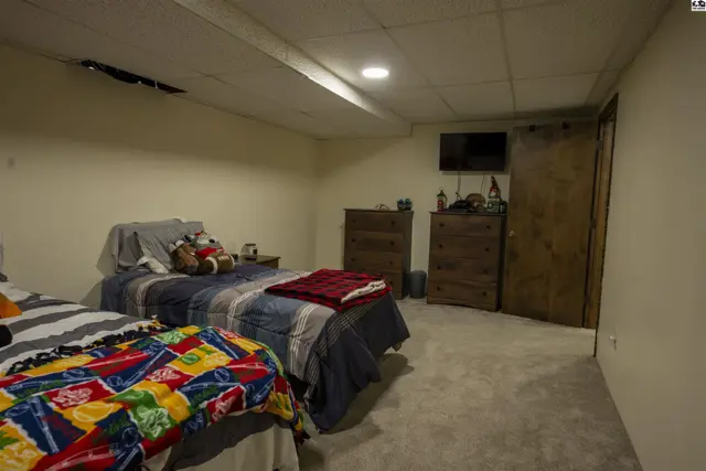 This finished basement room features two beds, dressers, and a television.
