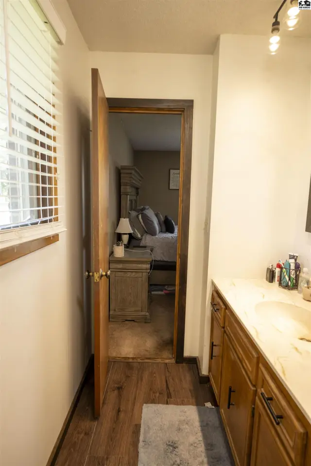 This bathroom features a double vanity with a marble countertop and a doorway leading to a bedroom.
