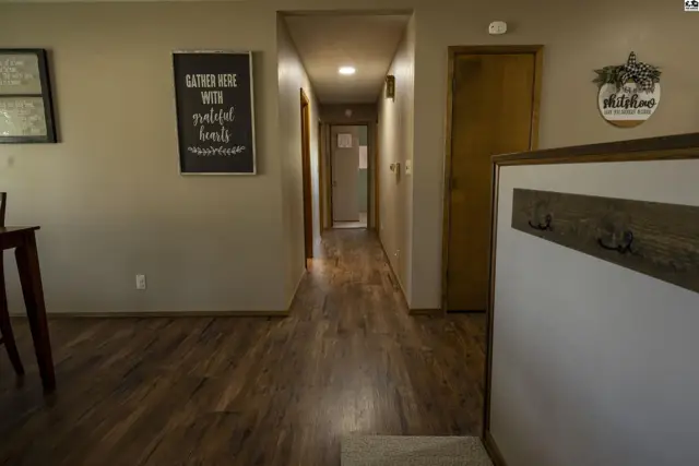 Hallway with wood-look flooring, neutral walls, and interior doors.