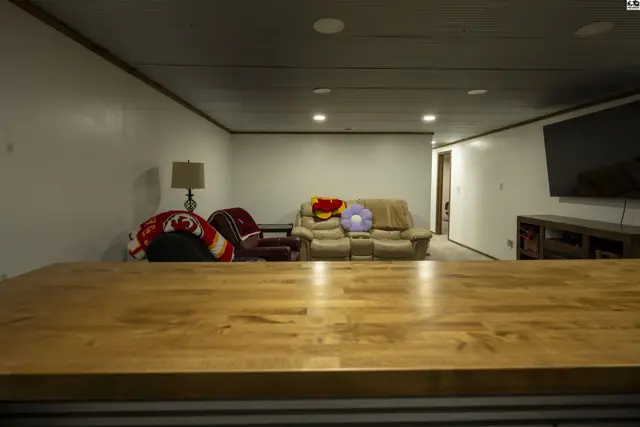 This finished basement features a sectional sofa, armchair, and a large television.