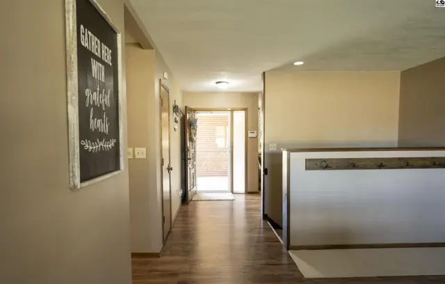 Hallway with wood-look flooring, neutral walls, and a built-in bench with hooks.