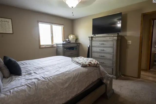 This bedroom features a king-size bed, a dresser, and a television.