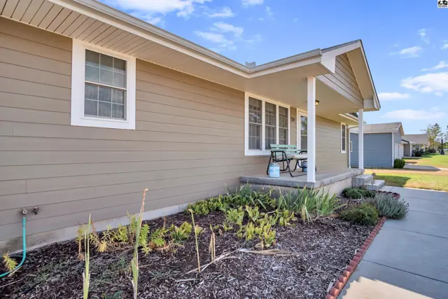 Covered front porch with seating area and landscaping.