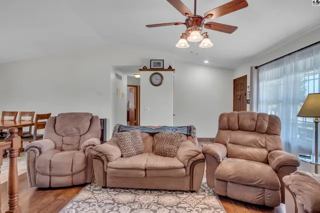 Living room features plush seating, a ceiling fan, and wood-look flooring.