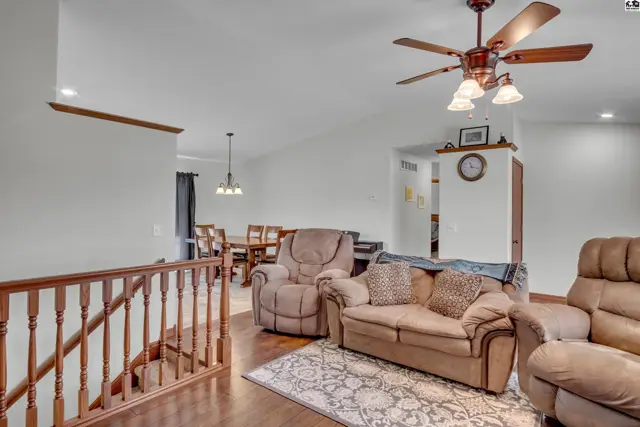 Spacious living area with vaulted ceilings, a ceiling fan, and a dining area visible beyond.
