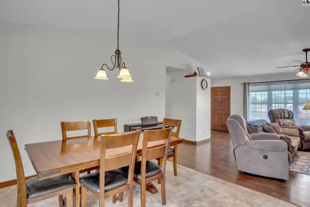 Dining area with wood table and chairs opens to a living room.