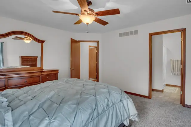 Spacious bedroom with a large dresser, mirror, and access to additional rooms.