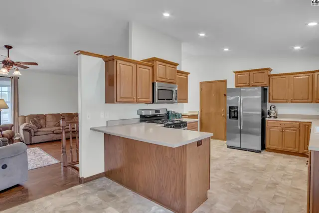 Spacious kitchen features wood cabinetry, stainless steel appliances, and a large island.