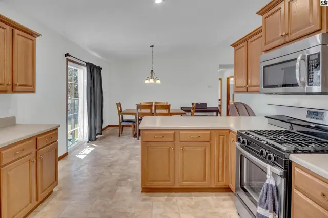 This kitchen features light wood cabinetry, stainless steel appliances, and a tiled floor.