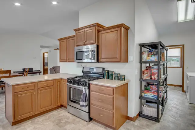 Spacious kitchen features wood cabinetry, stainless steel appliances, and ample counter space.