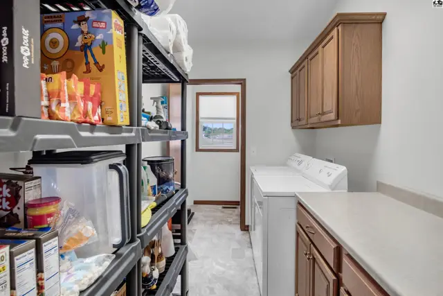 Laundry room with white washer, dryer, and wood cabinetry.