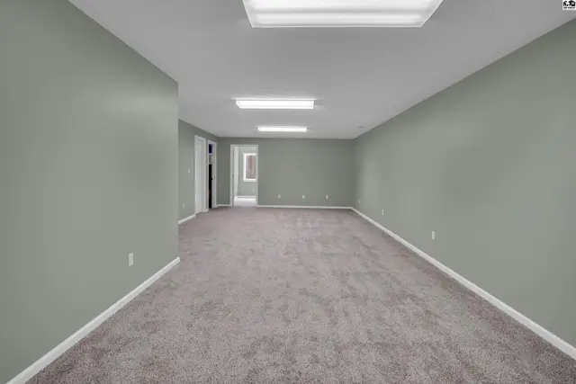 Spacious room with carpeted floor, neutral walls, and overhead lighting fixtures.