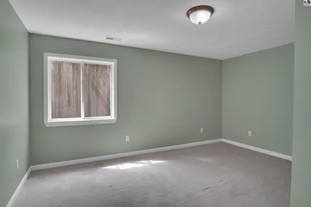 This room features light green walls, grey carpet, and a single window.