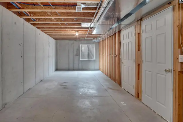 Unfinished basement with concrete walls, floor, and two interior doors.