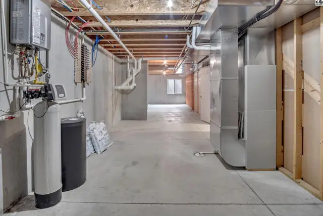 Unfinished basement with concrete floors, exposed ceiling joists, and utility hookups.