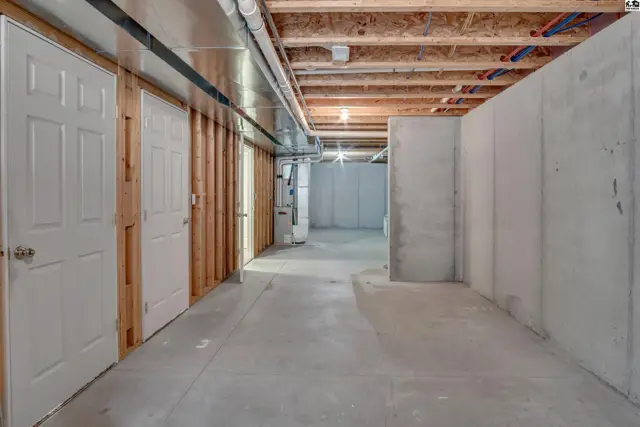 Unfinished basement with concrete floors, walls, and exposed ceiling joists.