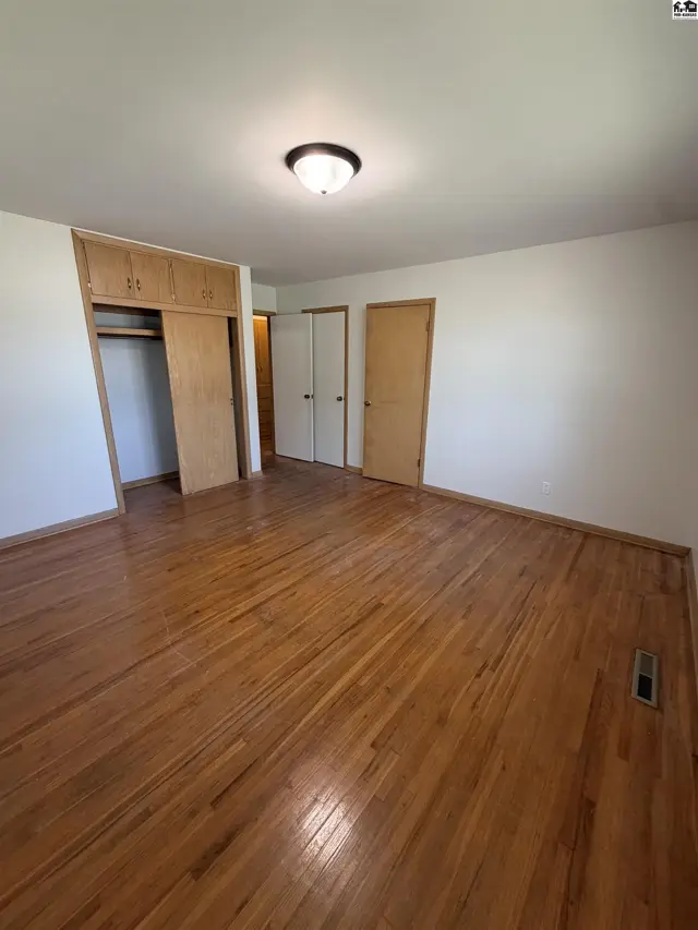 Spacious room with hardwood floors, built-in closet, and overhead lighting.