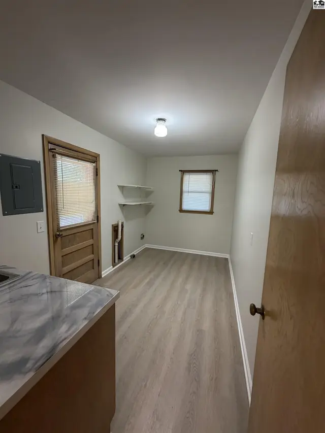 This room features light wood-look flooring, white shelves, and a wooden door.