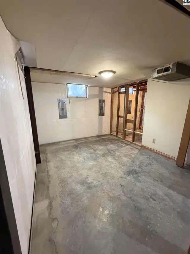 Unfinished basement with concrete floor, exposed studs, and a window.