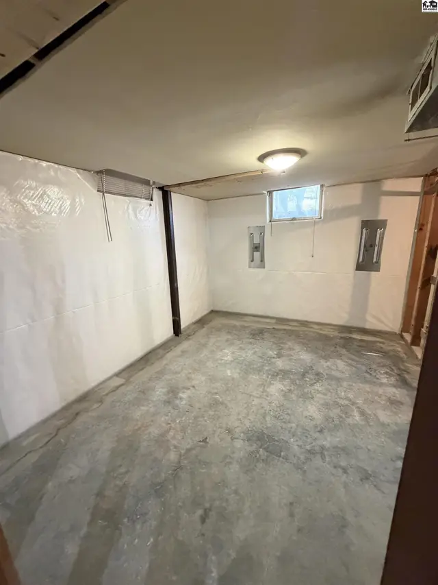 Unfinished basement with concrete floor, white walls, and a small window.