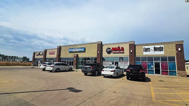 This commercial building features multiple storefronts with large windows and ample parking.