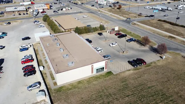 This commercial building features a light-colored exterior with a paved lot and surrounding landscaping.