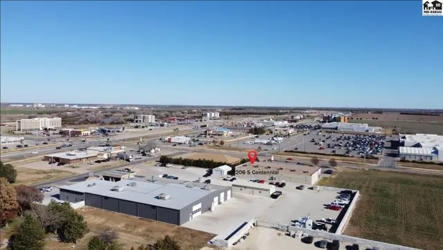This commercial property features a large, modern building with ample parking and surrounding undeveloped land.