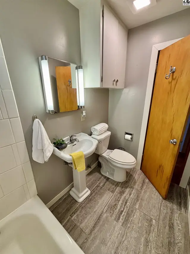 This bathroom features a pedestal sink, toilet, and a bathtub with white tile.