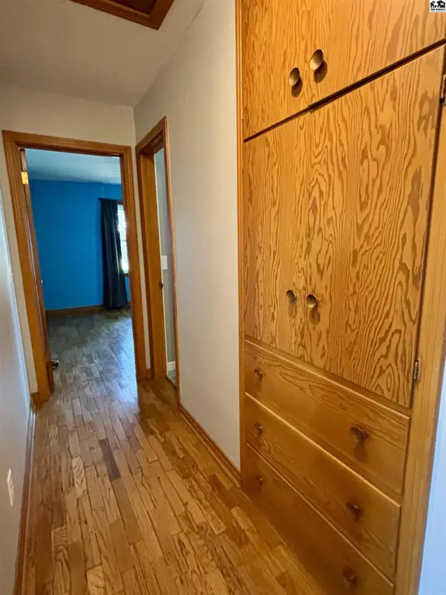 Hallway with hardwood floors and a large built-in wooden cabinet.
