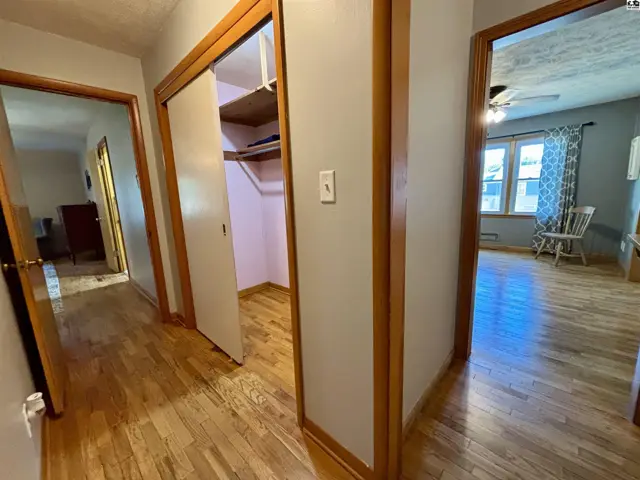 Hallway with wood floors, closet, and doorways to rooms.