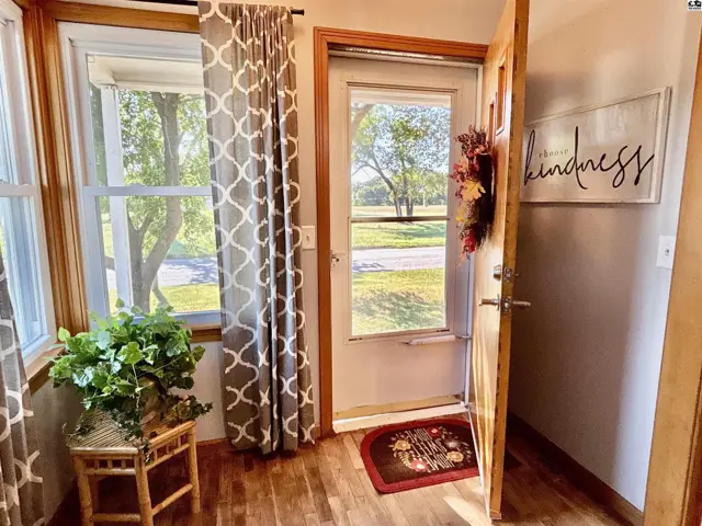 Wood-paneled entryway features a glass-paned door, large windows, and hardwood floors.