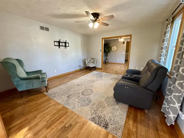 Living room features hardwood floors, a ceiling fan, and a large patterned rug.