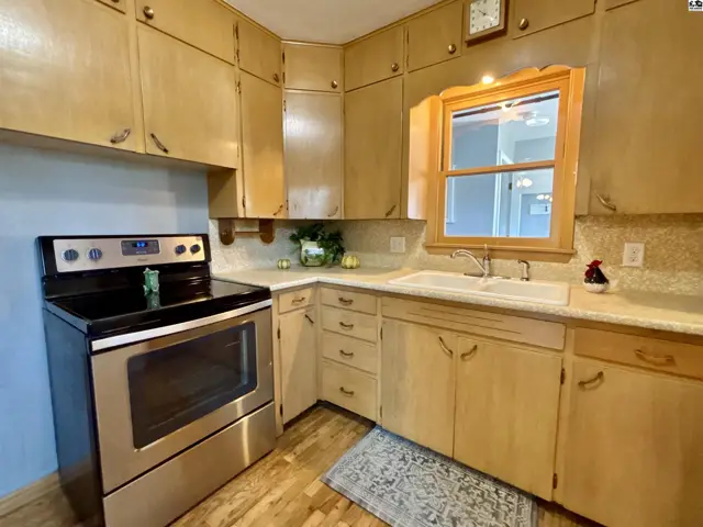 Kitchen features light wood cabinetry, a stainless steel range, and a double sink.