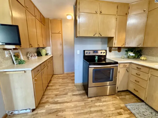 This kitchen features light wood cabinetry, laminate countertops, and a stainless steel range.