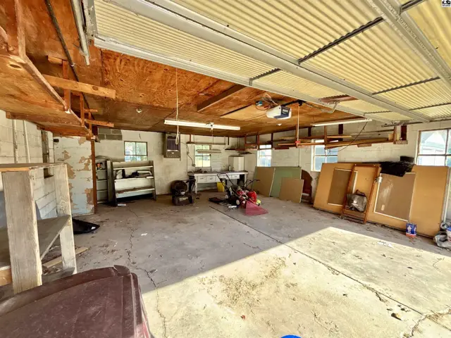 Spacious garage with concrete floor, exposed ceiling joists, and overhead lighting.