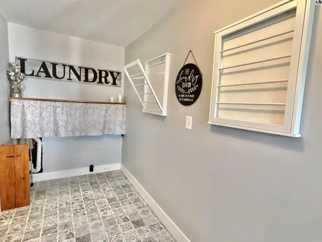 This laundry room features patterned tile flooring, wall-mounted drying racks, and a wooden cabinet.