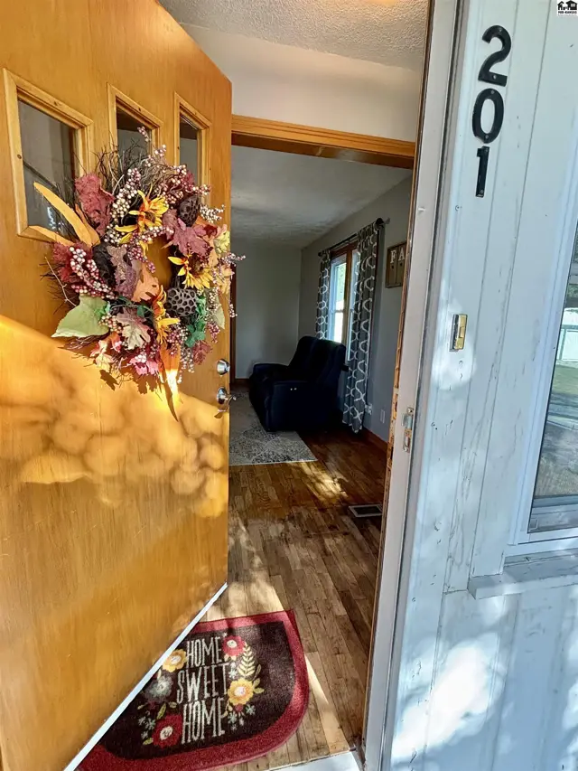 Wooden front door with glass panels opens to a living area with hardwood floors.