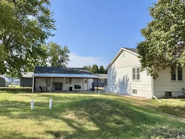 Exterior view of a light-colored house with a covered patio and grassy yard.