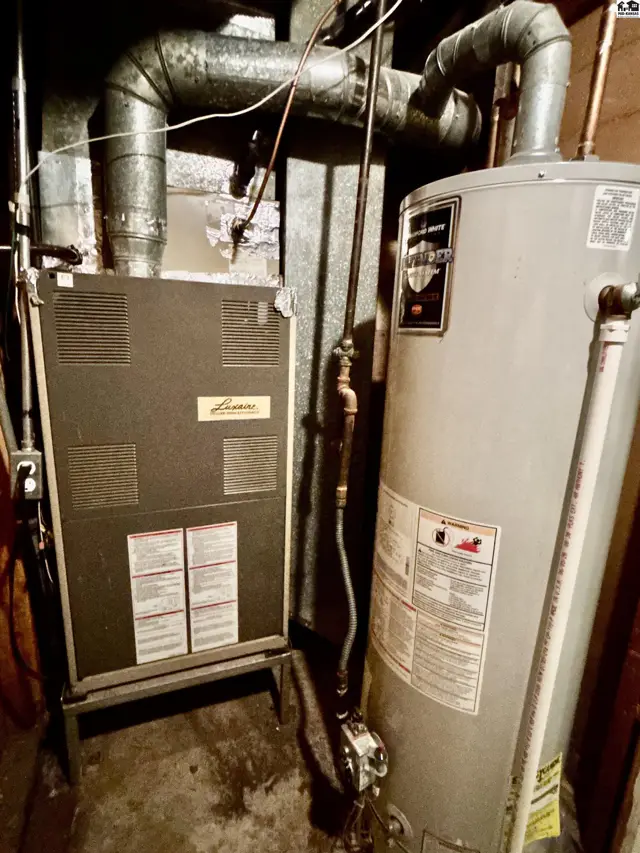 A furnace and water heater are installed with metal ductwork and piping.
