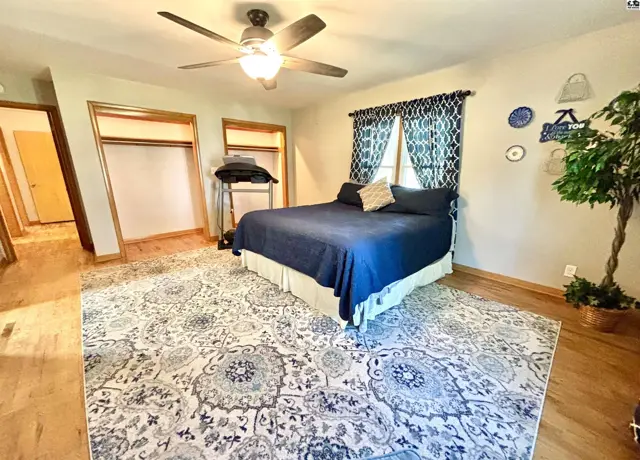 Spacious bedroom with a ceiling fan, large rug, and two closets.