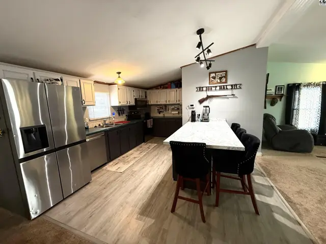 Spacious kitchen features stainless steel appliances, ample cabinetry, and a large island with seating.