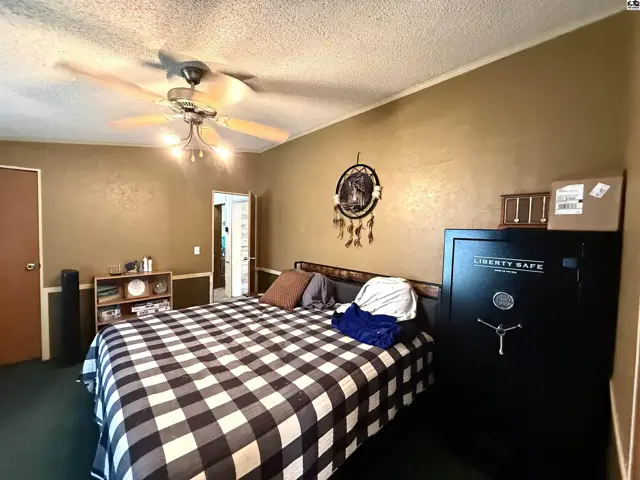 Spacious bedroom with a large bed, ceiling fan, and a wall safe.