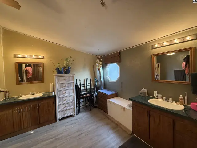 This bathroom features two vanities, a large mirror, and a white dresser.