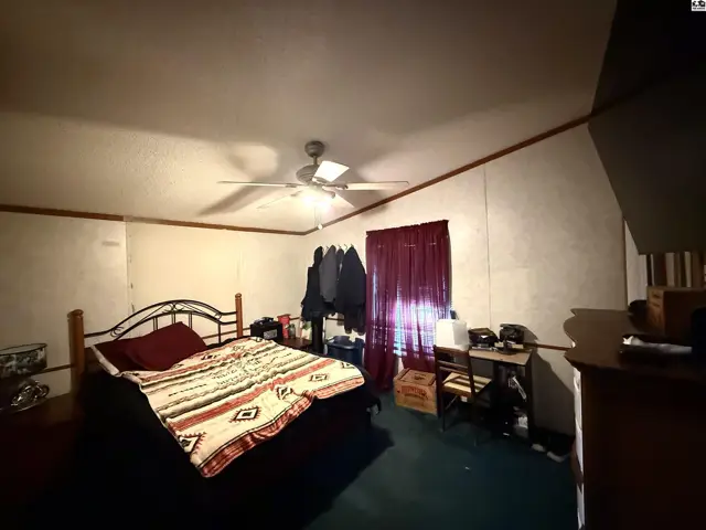 This bedroom features a metal-frame bed, a ceiling fan, and a window with burgundy curtains.