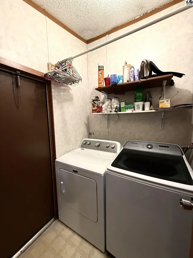 This laundry room features a white dryer, a white washing machine, and a metal hanging rod.