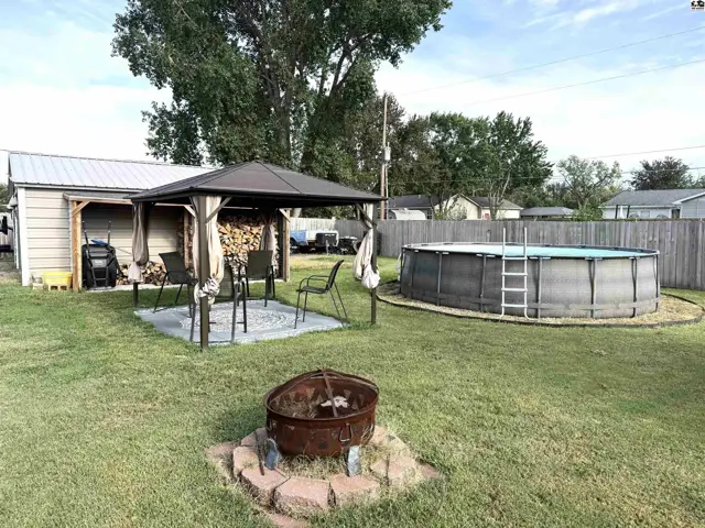 This backyard features a fire pit, gazebo, and above-ground swimming pool.