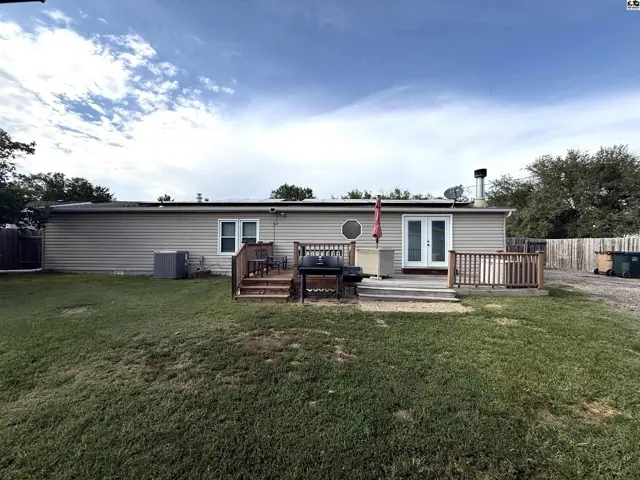 This home features a large wooden deck with a built-in grill and a fenced backyard.