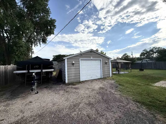 Two-car garage with a white door, adjacent to a fenced yard with a gazebo.