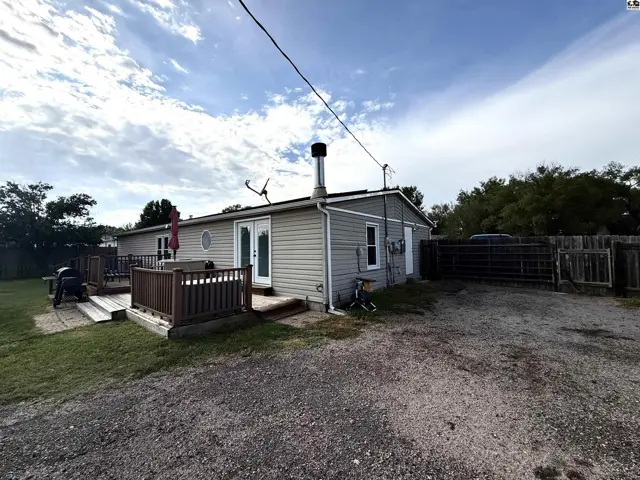 This home features a large wooden deck and a gravel driveway.