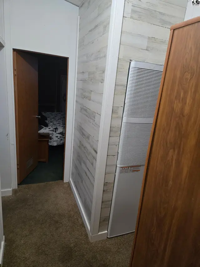 Carpeted hallway features wood-look paneling and a large vertical air conditioning unit.